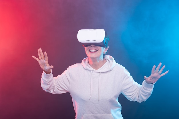 Passionné femme d'âge moyen en pull regarde un nouveau film avec des lunettes de réalité virtuelle sur rouge