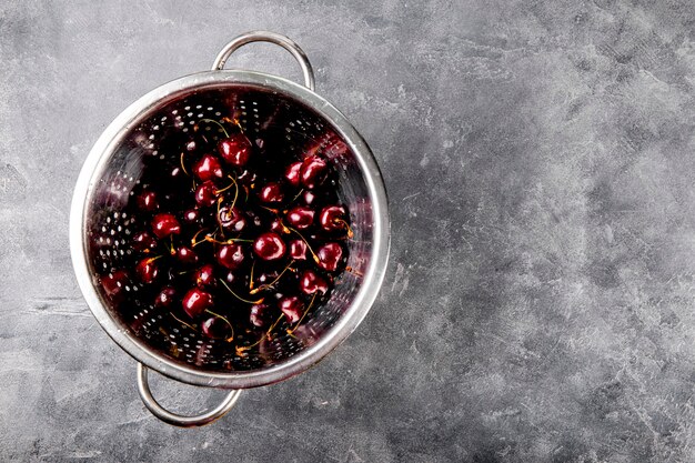 Une passoire cerises mûres sur fond gris baies d'été sur la table