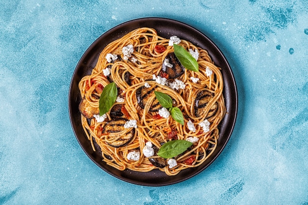 Pasta alla Norma - cuisine italienne traditionnelle avec aubergine, tomate, fromage et basilic, vue du dessus.