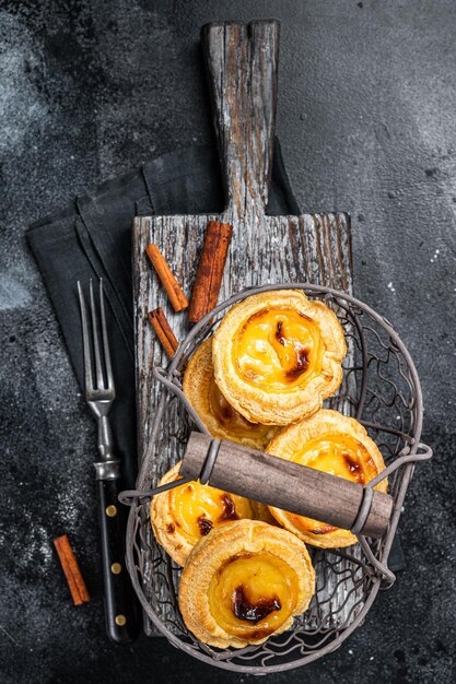 Photo pasteis de nata traditionnel de lisbonne dans un panier fond noir vue de dessus