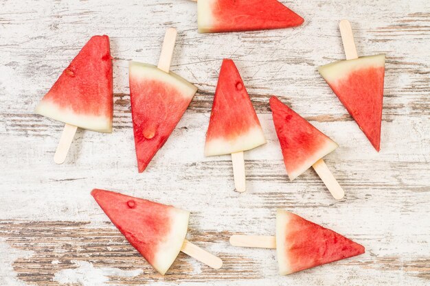 Pastèque en forme de sucettes glacées sur un fond en bois