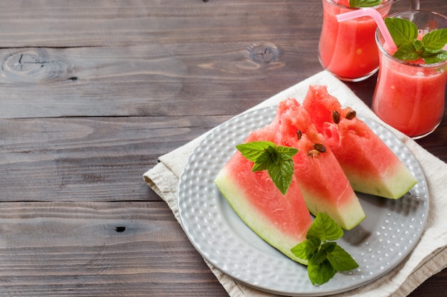 Pastèque tranchée sur une assiette avec des feuilles de menthe et un smoothie frais à la pastèque