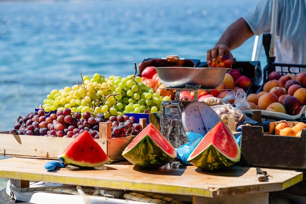 Photo des pastèques, des raisins verts et violets, des pêches dans un bateau à brela, en croatie