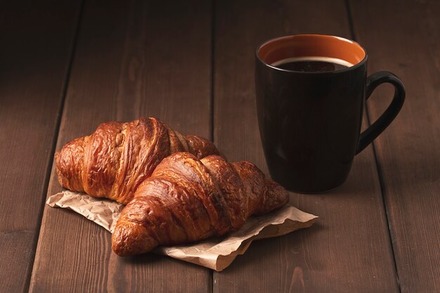 Pastriescroissants sur une table en bois marron avec une tasse de café petit-déjeuner sans style rustique de personnes