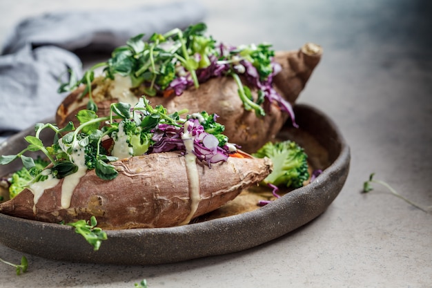 Patates douces au four farcies au quinoa, brocoli et chou, fond sombre.