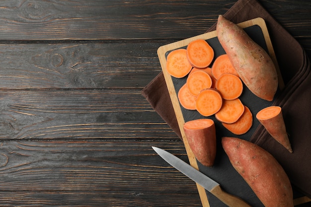 Patates douces, couteau, planche et serviette sur une surface en bois