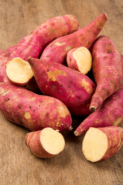 Patates douces crues sur gros plan de l'espace en bois. Légume frais.