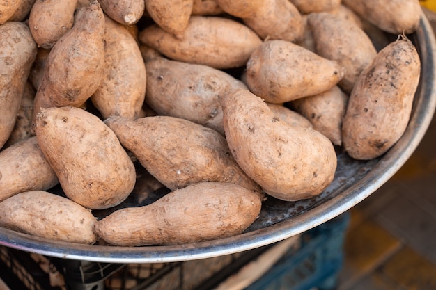 Patates douces nommées batata sur le marché du comptoir sur fond de citrons.