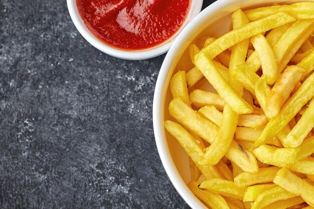 Patates frites avec sauce sur fond sombre