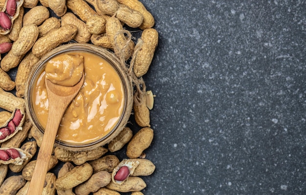 Pâte d'arachide dans un bocal ouvert cacahuètes crémeuses au beurre d'arachide dispersées vue de dessus