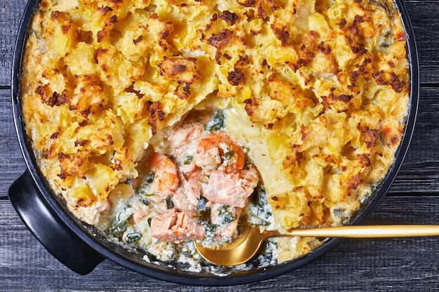 Photo pâté au saumon avec aiglefin fumé, crevettes, épinards, garni de purée de pommes de terre dans un plat allant au four, cuisine anglaise