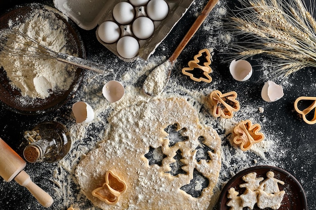 Pâte à biscuits au gingembre enroulée sur une table et découpée à l'aide de moules