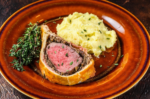 Pâte de boeuf Wellington avec pommes de terre en purée sur une plaque rustique