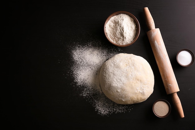 Pâte crue avec ingrédients et rouleau à pâtisserie sur la table de la cuisine