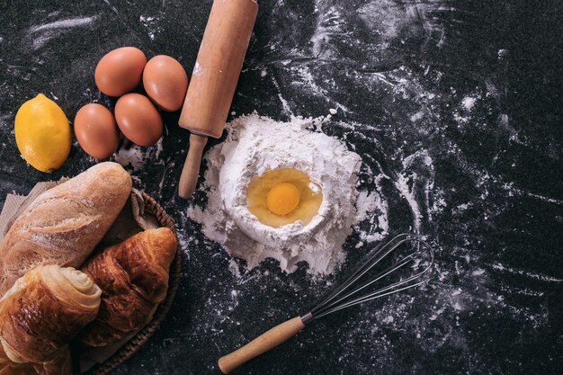 pâte crue pour le pain avec des ingrédients sur fond noir vue supérieure