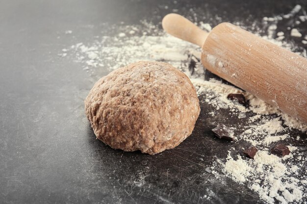 Pâte crue avec rouleau à pâtisserie sur table