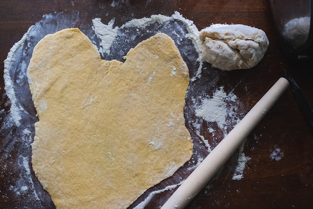 Pâte crue sans levain sur la table de la cuisine, rouleau à bascule, mise au point sélective