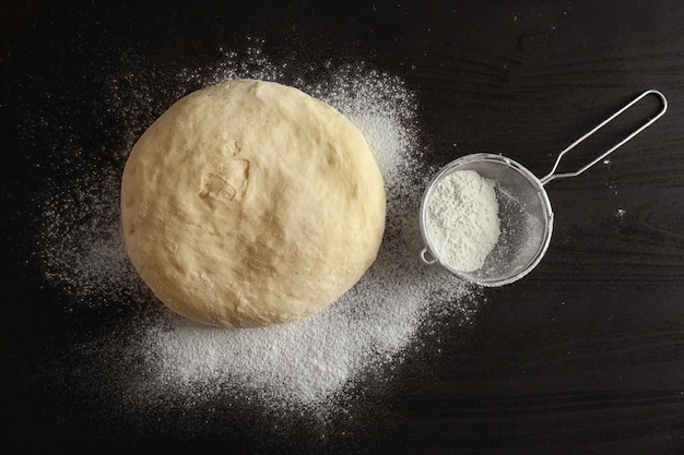 Pâte crue et tamis sur la table de la cuisine