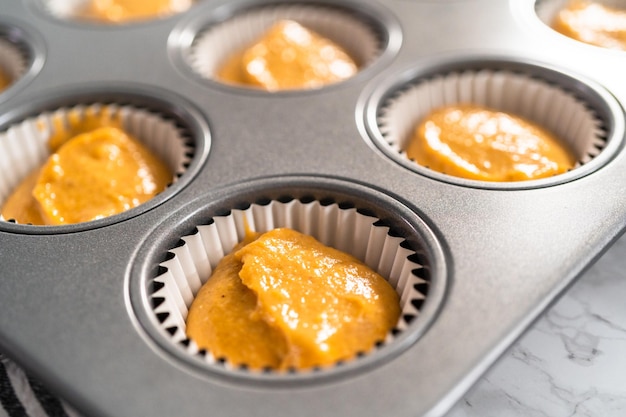 Pâte à cupcake aux épices à la citrouille dans un moule à cupcake avec doublures.