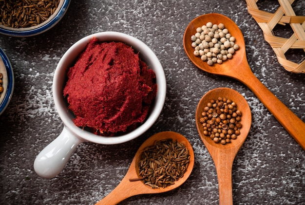 Pâte de curry épicée thaïlandaise avec trois ingrédients principaux sur des cuillères en bois comme le poivre blanc, le cumin et les graines de coriandre - Assaisonnement aux herbes thaï