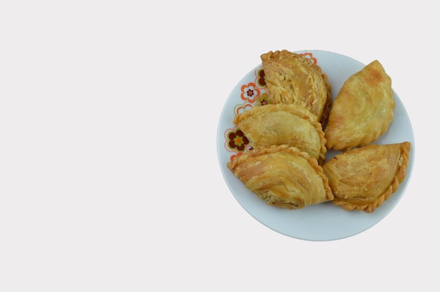 Pâte feuilletée au curry sur une plaque blanche sur fond blanc