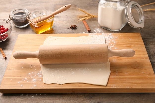 Pâte feuilletée crue avec rouleau à pâtisserie sur planche de bois