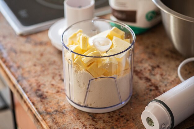 Pâte feuilletée dans la fabrication de farine et de beurre dans une tasse de mélangeur Ustensiles de cuisine concept de style maison