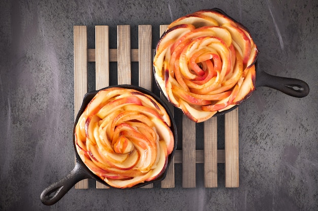 Pâte feuilletée faite maison avec des tranches de pomme en forme de rose cuites dans une poêle de fer sombre