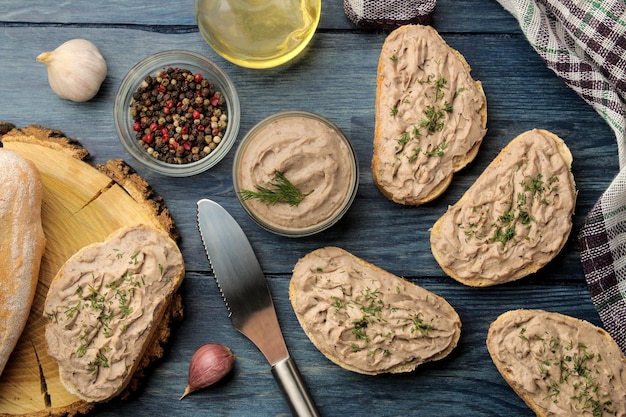 Pâté de foie de poulet frais fait maison avec des herbes sur du pain sur une table en bois bleue. Un sandwich. vue de dessus