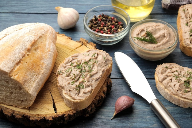 Pâté de foie de poulet frais fait maison avec des herbes sur du pain sur une table en bois bleue. Un sandwich.