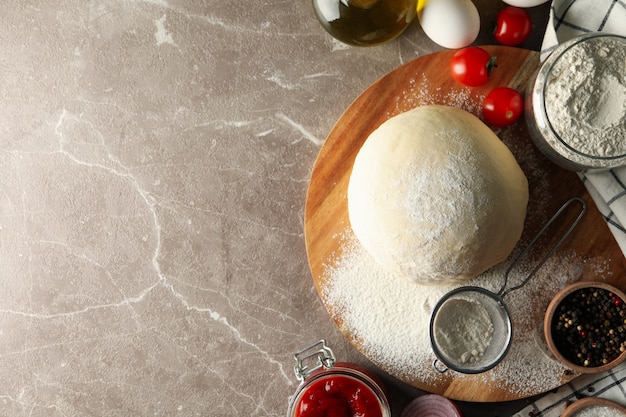 Pâte et ingrédients pour la cuisson de la pizza sur fond gris