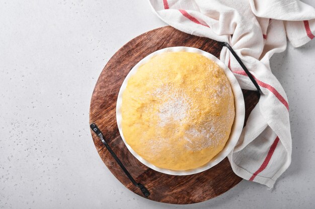 Pâte à levure crue à la citrouille dans un bol blanc recouvert d'une serviette sur la table de cuisine farinée, idée de recette. Concept maison faisant du pain, des petits pains ou du cinnabon ou faire de la pâte.