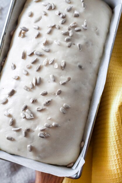 Pâte de levure crue en forme d'étain, prête à cuire du pain aux graines de tournesol