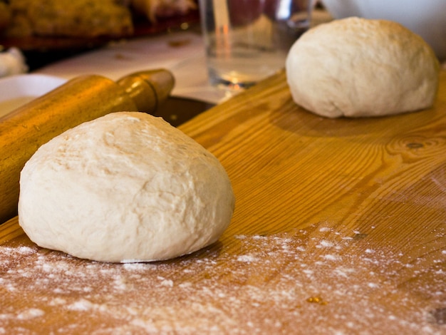 Pâte à levure en farine sur une planche de bois avec rouleau à pâtisserie