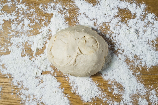 Pâte à levure sur une table en bois saupoudrée.