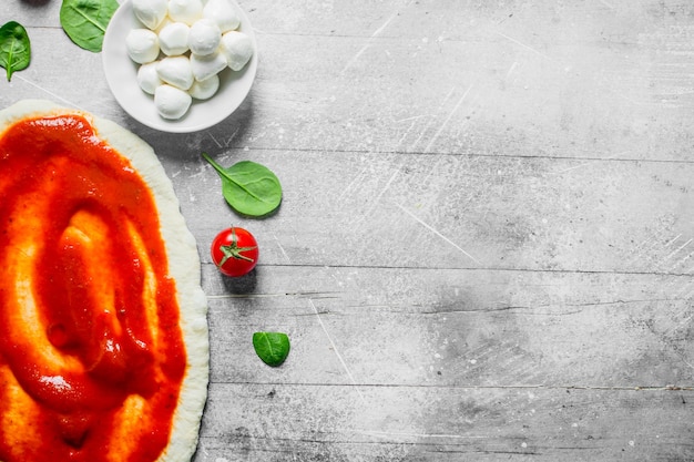 Photo pâte à pizza crue avec pâte de tomate mozzarella et épinards