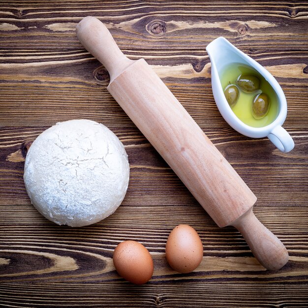 Pâte à pizza crue et rouleau à pâtisserie sur fond en bois