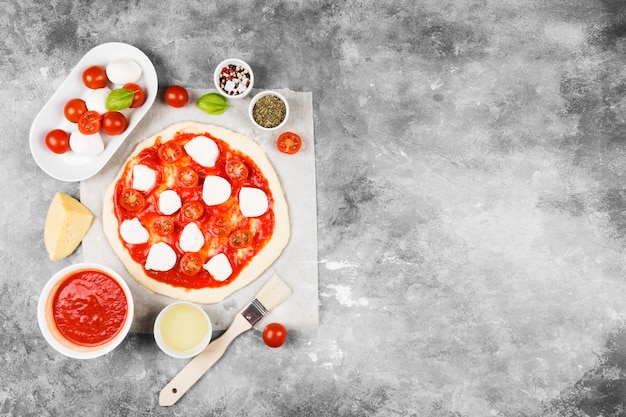 Pâte à pizza et ingrédients pour pizza sur espace gris. Vue de dessus, espace copie. Espace alimentaire