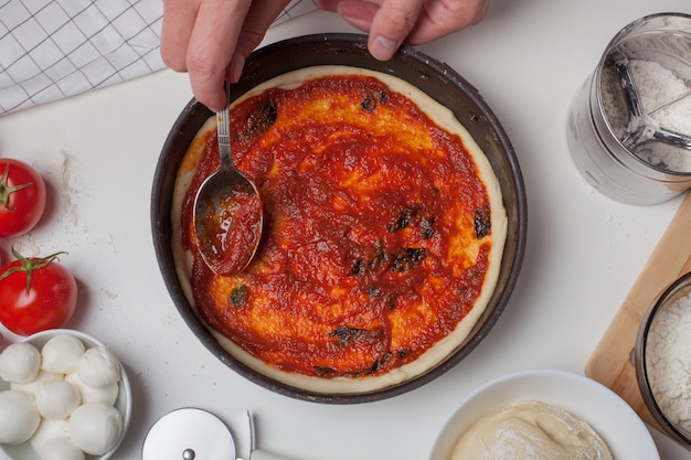 Pâte à pizza avec ingrédients et sauce tomate.