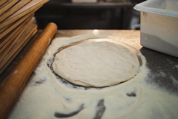 Pâte à pizza non cuite entourée de farine sur la table de la cuisine dans une boulangerie artisanale