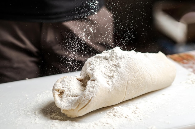 Pâte sur planche à découper sur laquelle on verse de la farine Préparation de pâte à pain pour divers produits