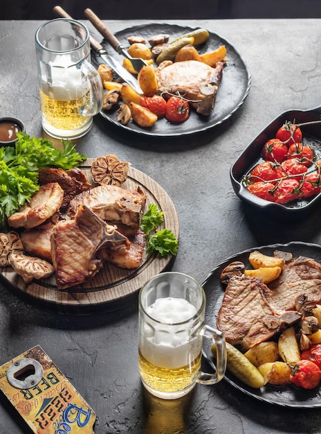 Photo pâte de porc grillée au barbecue servie avec des légumes et de la bière sur une table de fête brune verticale