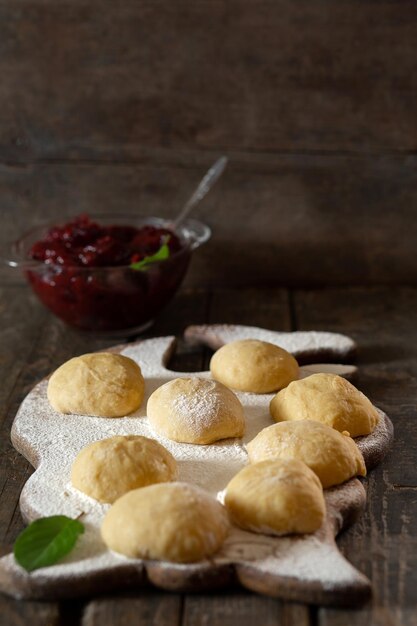 Pâte pour galettes avec confiture de cerises sur une table en bois sur une planche avec de la farine