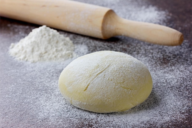 Pâte avec rouleau à pâtisserie et farine sur une surface en pierre