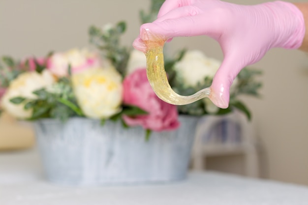 Pâte de sucre ou miel de cire à épiler avec des gants roses, mains de cosmétologue au salon spa