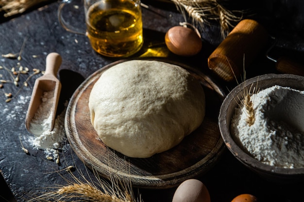 Pâte sur la table sur un fond sombre. Farine, beurre, oeufs