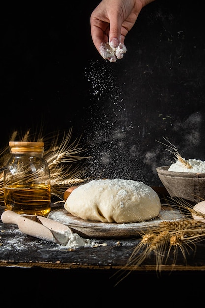 Pâte sur la table sur un fond sombre. Farine, beurre, oeufs