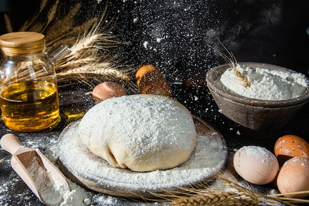 Pâte sur la table sur un fond sombre. Farine, beurre, oeufs