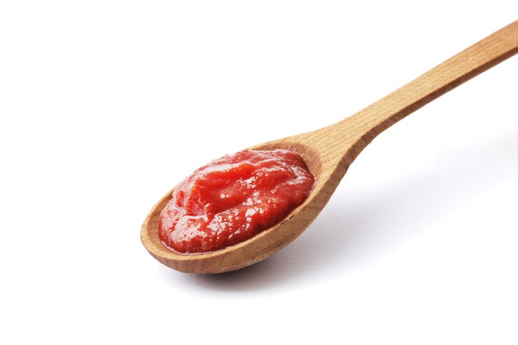 Pâte de tomate sur une cuillère en bois isolé sur fond blanc