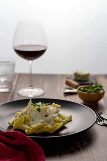 Pâtes 4 macaronis au fromage penne sur table en bois Verre de vin sur l'arrière-plan mise au point sélective